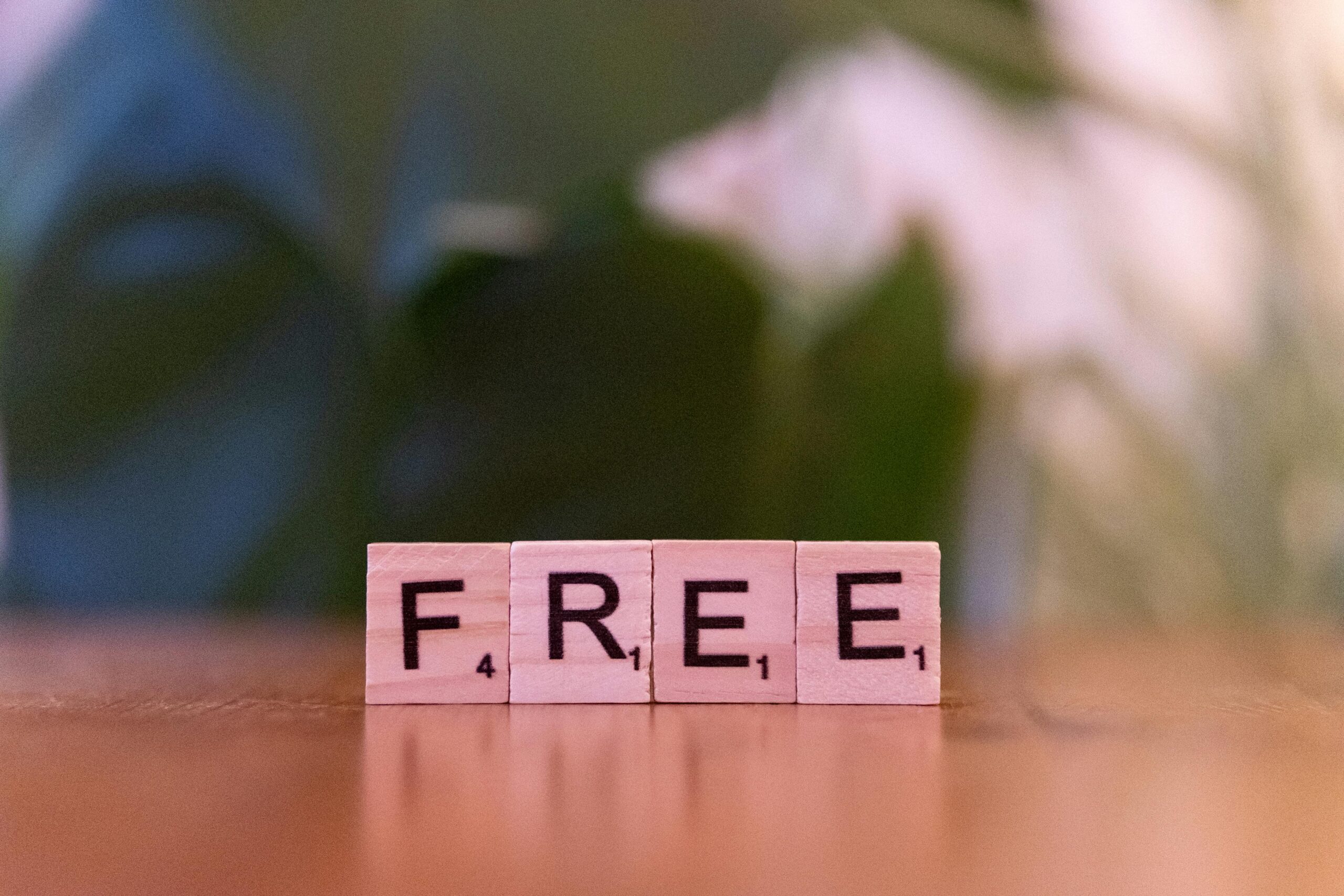 Close-up of wooden Scrabble tiles spelling 'FREE' on a table.